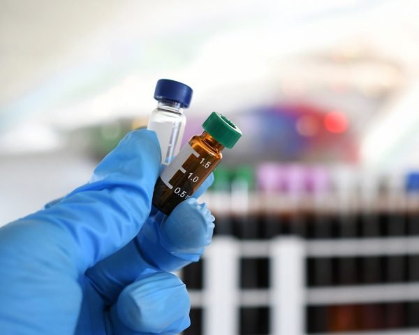 Lab tech holding LCMS testing vials in a laboratory for drug testing